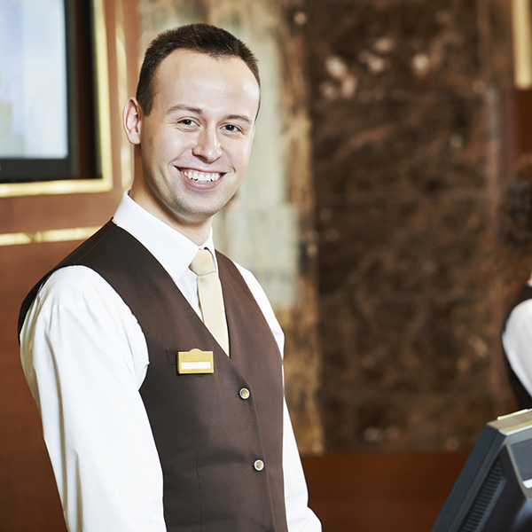 Happy receptionist worker standing at hotel counter